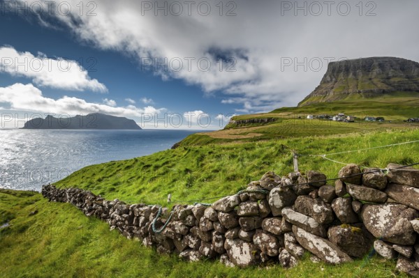 View of the island of Mykines, old stone wall, Gásadalur village, Vágar, Faroe Islands, Denmark,