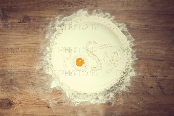 Flour on a wooden table, top view, inscription Pasta, with egg yolk, cooking, food concept, no
