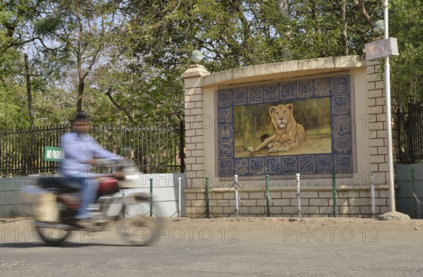 Motorcycle in front of the image of a lion, Asiatic Lion, outside the headquarters of the Forestry