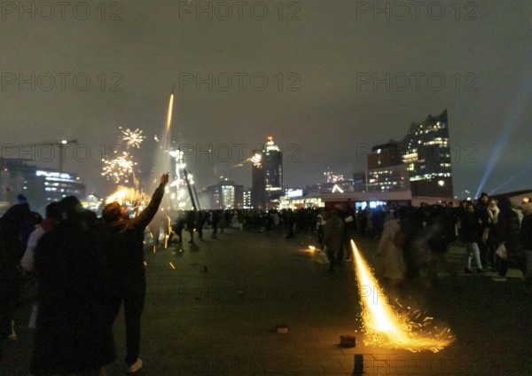 Person launches firework rocket from his hand, New Year's Eve 2025 on the Elbe promenade in