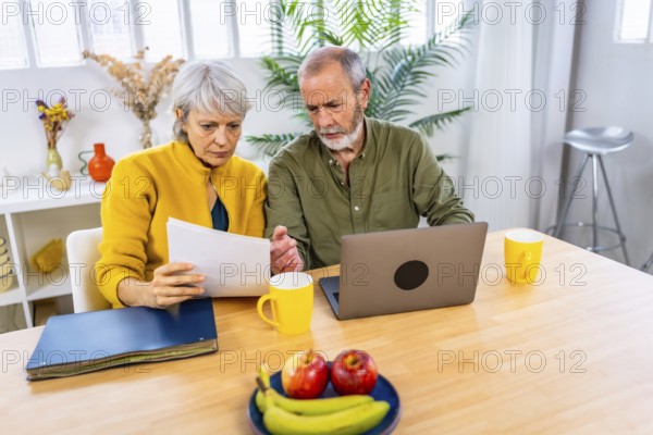 Paperwork in the living room where a senior couple with laptop for finance planning with retirement