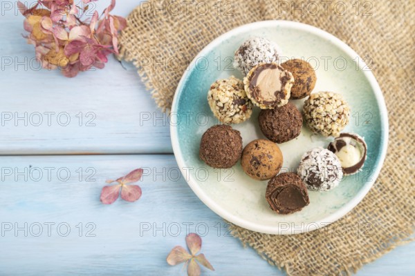 Chocolate truffle candies with cup of coffee on a blue wooden background and linen textile. top