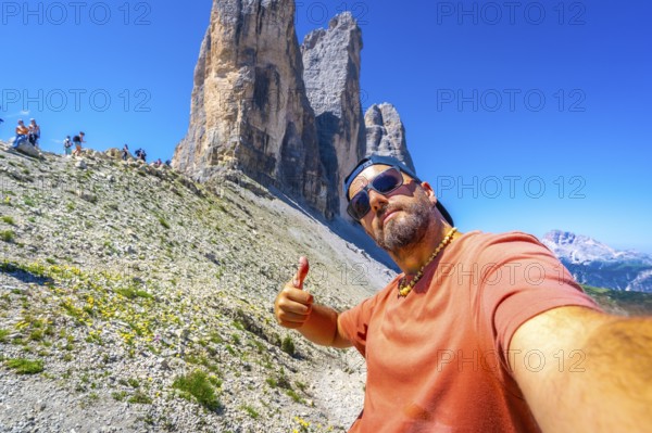 Tourist taking a selfie and making thumbs up gesture while hiking in the tre cime di lavaredo,