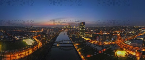 The lights of the European Central Bank (ECB) and the Frankfurt banking skyline glow in the evening