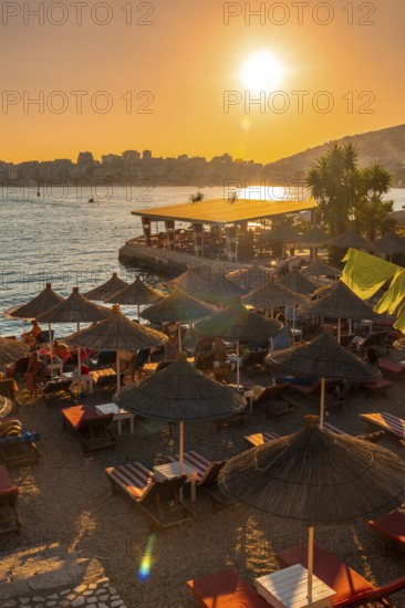 Beautiful resort with umbrellas and palm trees by the sea at sunset in Sarande or Saranda on the