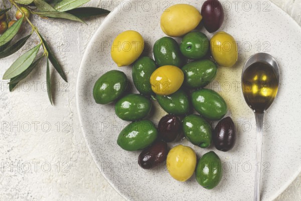 A mix of olives, a variety of Chalkidiki, verdi giganti and Kalamata, on a plate with a spoonful of