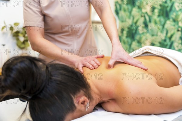Close-up cropped photo of an unrecognizable masseur giving a back massage to a woman lying on