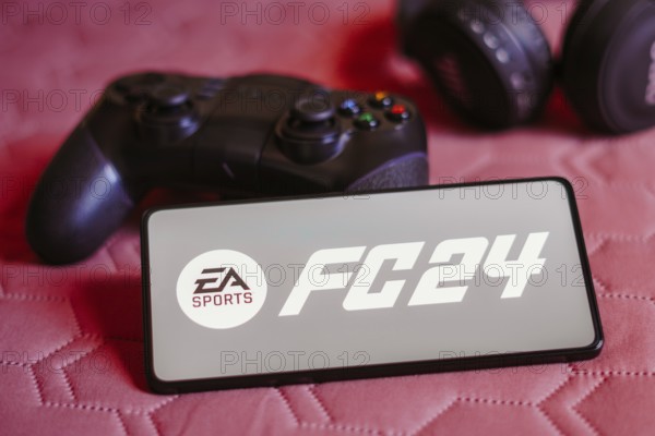 In this photo illustration, the EA SPORTS FC 24 logo is displayed on a smartphone screen, next to a
