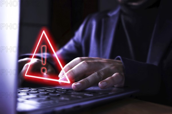 Hands of a businessman using the computer on fraudulent pages. Caution symbol of danger of hackers