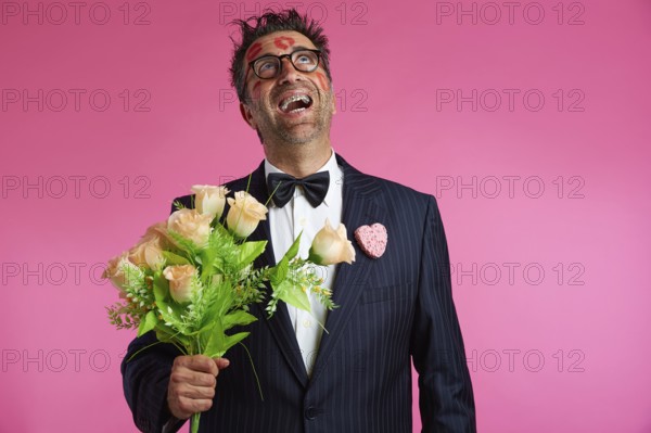 Nerd man with lipstick marks on face in Valentines Day and flowers