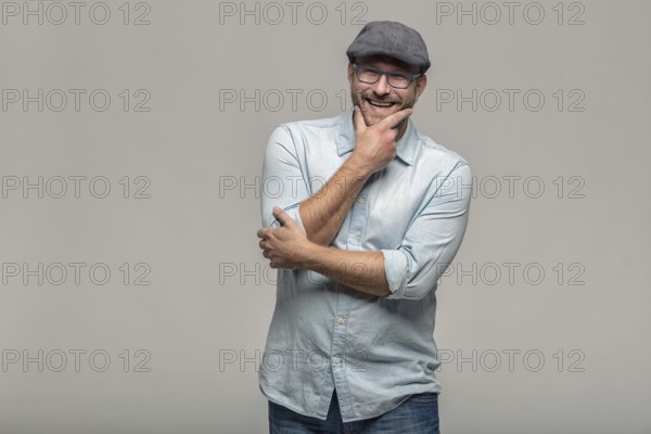 Thoughtful attractive middle-aged man with his finger to his mouth standing looking towards the