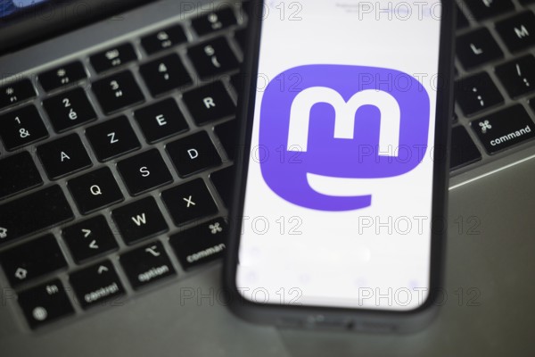 Logo of Mastodon, a new social networking service pictured here on a mobile phone above a keyboard