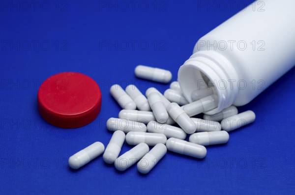 Large white pills fell from a large white bottle. Life without drugs and dependence on capsules of