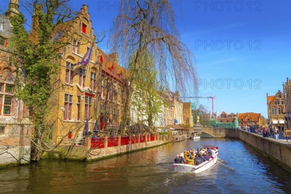 Bruges, Belgium, April 10, 2016: Scenic cityscape with medieval houses, boat with tourists and