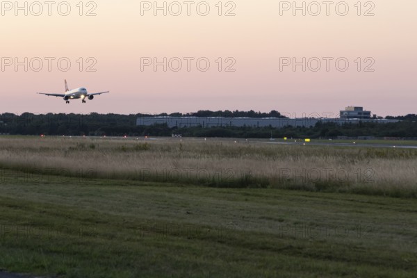 Passenger aircraft Airbus A320-214 of Austrian Airlines at dusk during landing at Hamburg Airport,