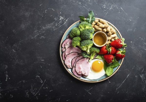 Ketogenic low carbs diet, top view, space for text. Plate on stone black background with keto