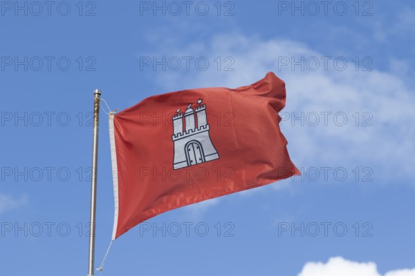 Red flag with the coat of arms of Hamburg against a blue sky in Hamburg, Germany, Europe