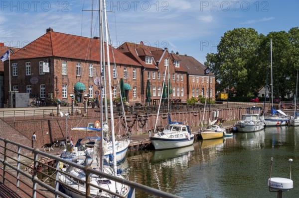 Sailing yachts on the promenade with brick houses and a terrace in sunny weather and blue sky,