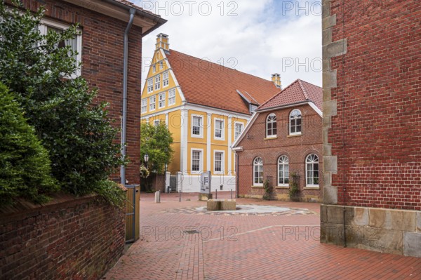 Idyllic alley with orange building and cobblestones between brick buildings, Lingen, Emsland, Lower