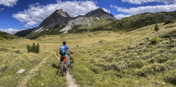 Mountain bikers on the Pass da Costainas with Piz Starlex and Piz Murtera with Foppa da Tamangur