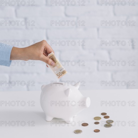 Close up woman s hand inserting fifty euro banknote piggybank desk. Beautiful photo