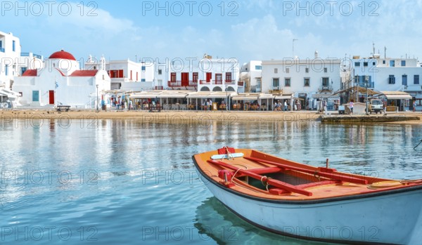Beautiful summer day sunshine on Greek island. Fishing boats moored at jetty. Whitewashed houses by