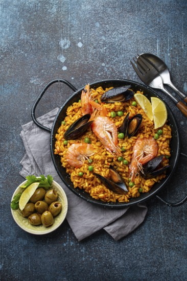 Classic dish of Spain, seafood paella in traditional pan on rustic blue concrete background top