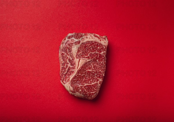 Raw fresh uncooked meat beef prime cut steak Ribeye on clean red background from above, beefsteak