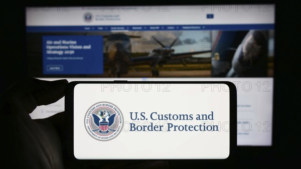 Stuttgart, Germany, 10-29-2023: Person holding mobile phone with seal of agency United States