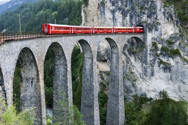 Red train of swiss Rhätische Bahn, Rhaetian Railway Company or Glacier Express on Viaduct