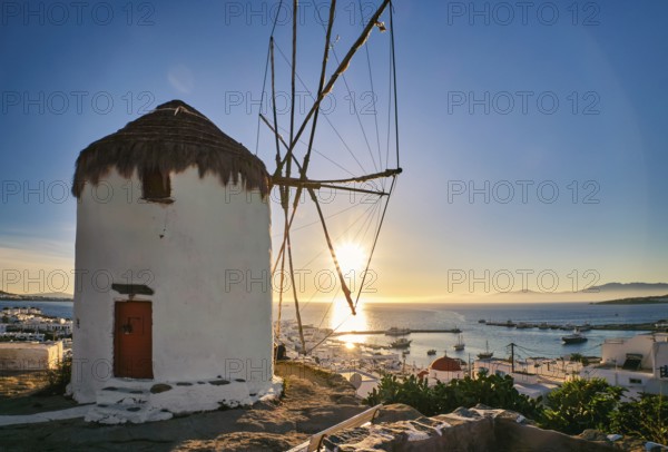 Romantic view of traditional Greek whitewashed windmill on hill. Chora town and harbor of Mykonos,