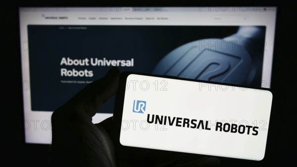 Stuttgart, Germany, 02-12-2024: Person holding smartphone with logo of Danish cobot company