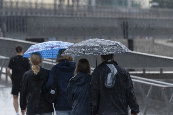 Symbolic picture weather, heavy rain in summer, thunderstorm, thunderstorm, tourists with umbrellas