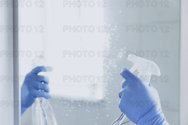 Cropped view of housekeeper woman hand in rubber blue gloves spraying chemical cleaner liquid to