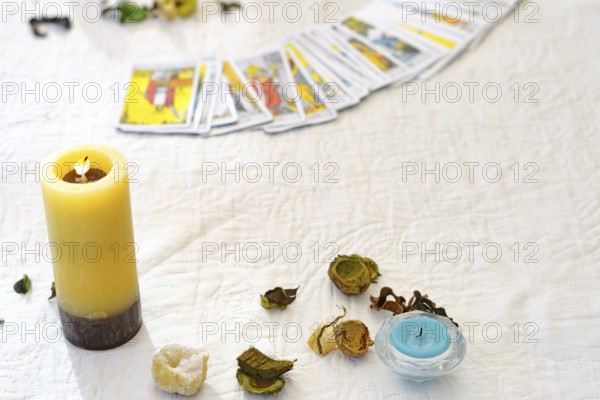 Table of a fortune teller with tarot cards, candles, quartz stones, crystal ball on a white