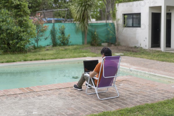 Latin man working on his laptop in the pool