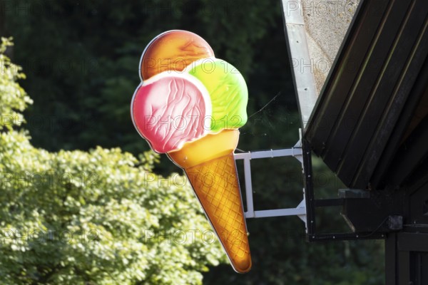 Illuminated sign in the shape of a colourful ice cream cone at an ice cream parlour in Planten un