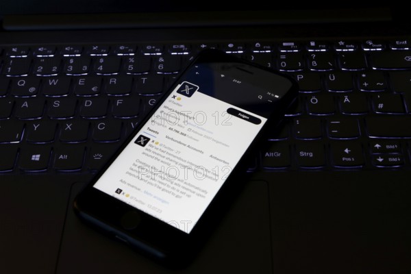 Symbolic image social media, close-up of a smartphone on an illuminated computer keyboard with X