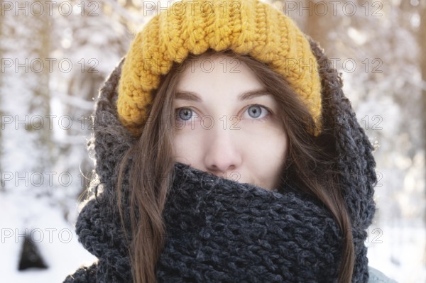 Portrait of a smiling young caucasian woman in a bright woolen hat and scarf, against the backdrop