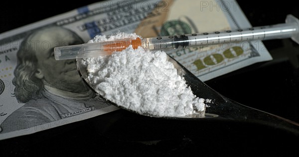 Dollar Bank notes and Siringa with Powder Drug against Black Background
