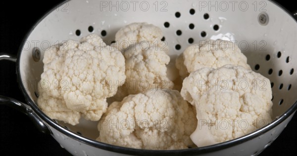 Water falling on Cauliflower (brassica) oleracea, against Black Background