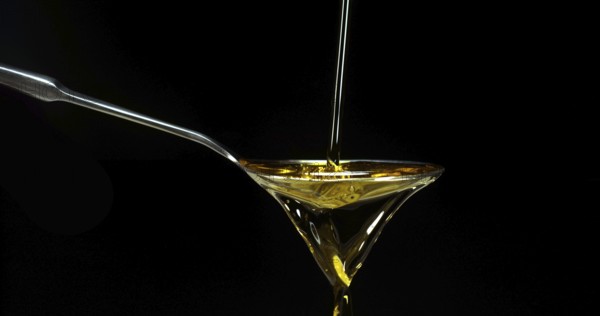 Olive Oil, Falling in a Spoon against Black Background
