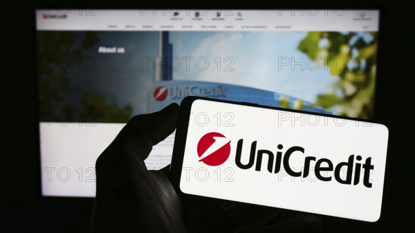 Stuttgart, Germany, 06-17-2023: Person holding mobile phone with logo of Italian financial company
