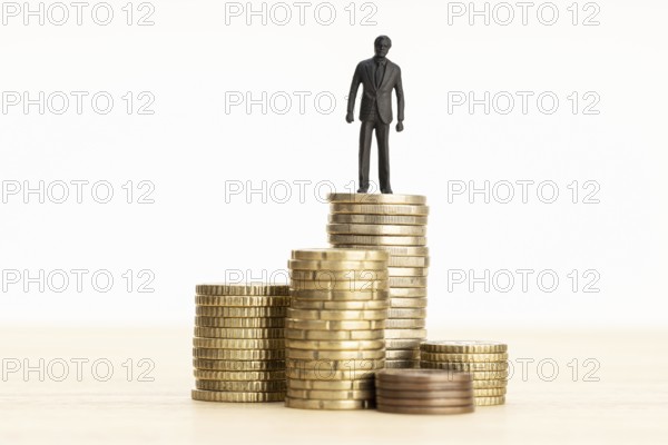 Wealth, making money, wage growth concept. Businessman figurine standing on a pile of coins. Copy