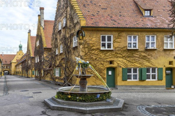 Building in the historic residential complex Fuggerei and Fuggerei Brunnen in the old town of