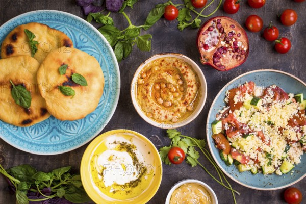 Table served with middle eastern traditional vegetarian dishes. Hummus, tahini, pitta, couscous