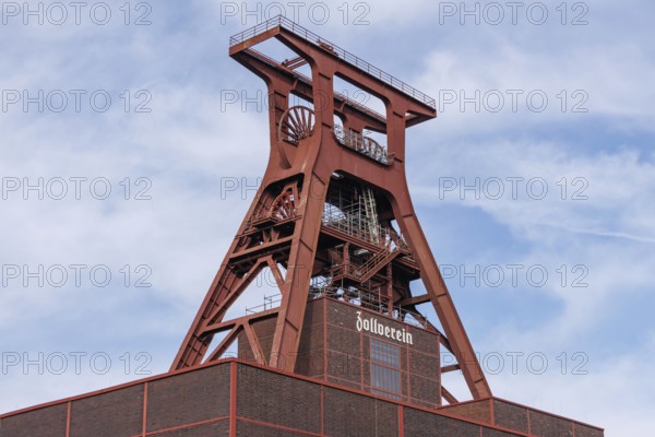 The historic winding tower of the Zeche Zollverein in front of a blue sky with clouds, essen. ruhr