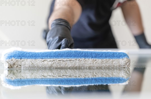 A professional window cleaner using a window cleaning washer sleeve to cleanse a large fold down