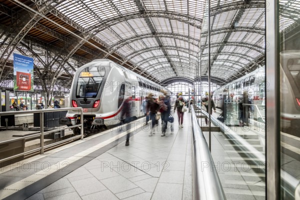 Travellers waiting for trains in a station concourse with an impressive roof, Leipzig Central