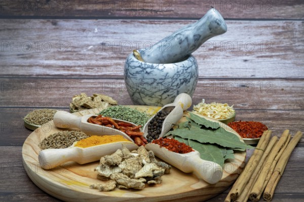Different types of spices in wooden spoons on a wooden disk ginger, cayenne, pepper, cinnamon,